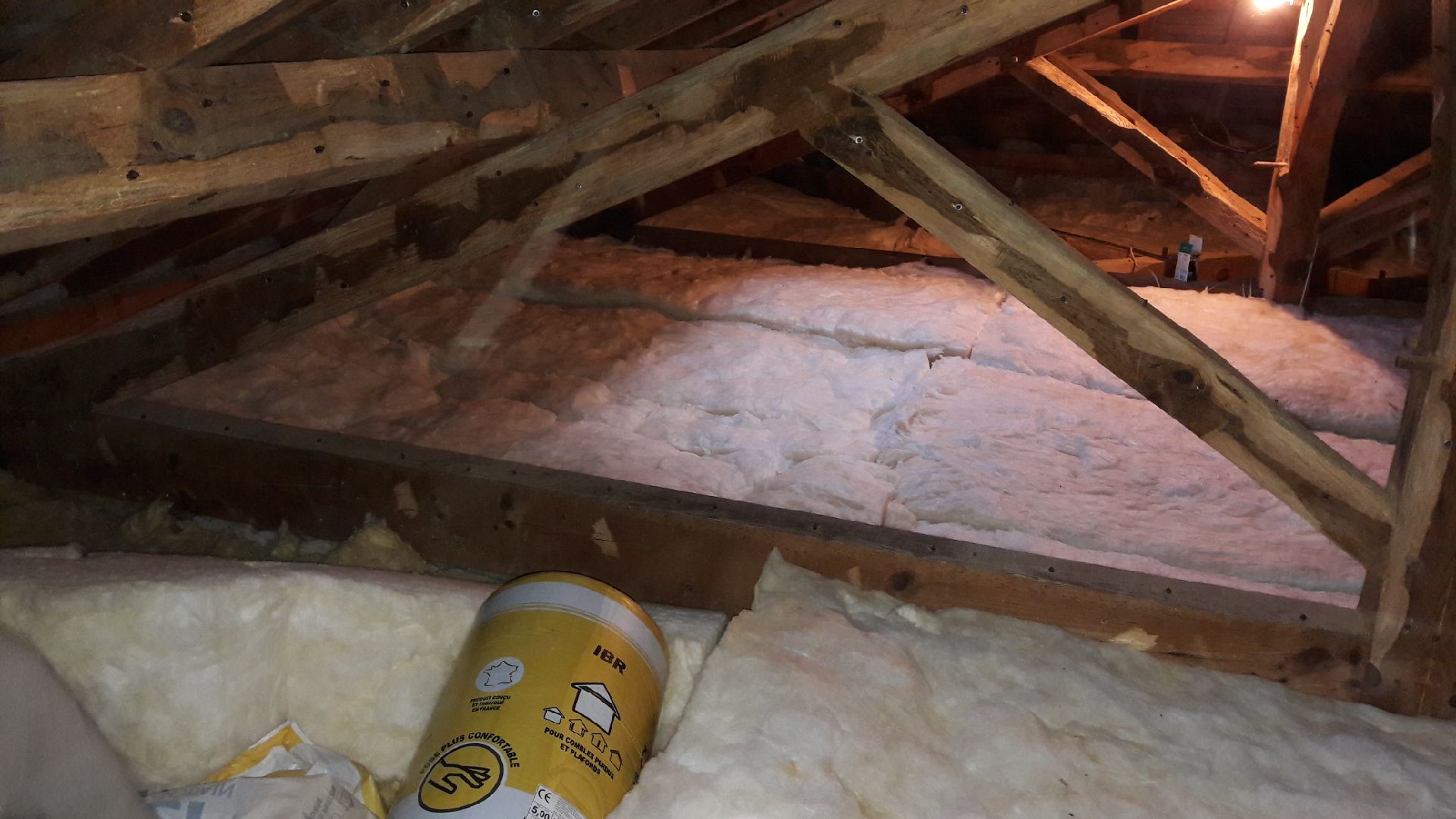 Pose de rouleaux d'isolant en laine de verre dans les combles — free download